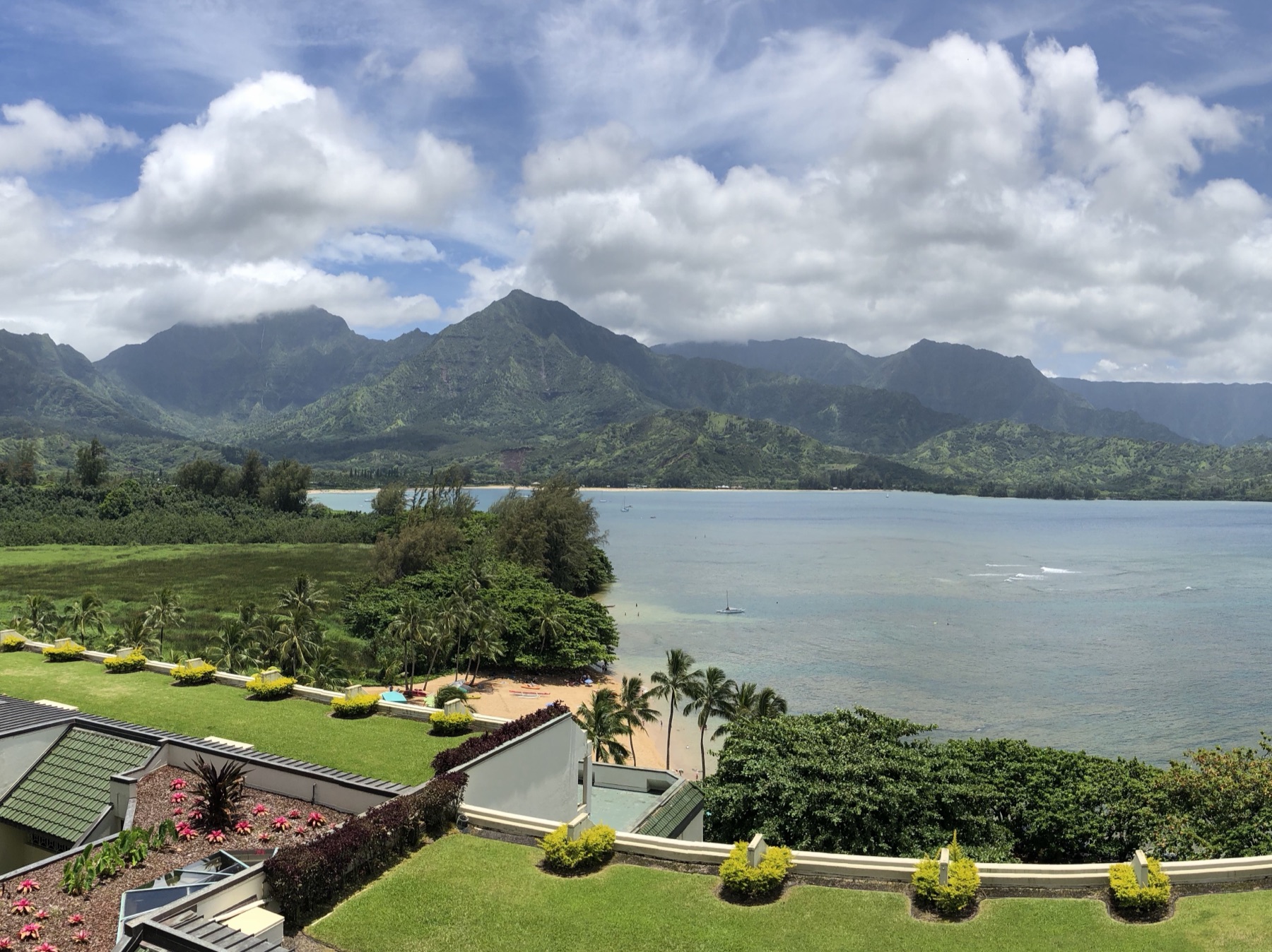 A tropical bay below green, cloud-topped mountains